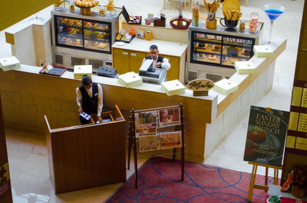 two people standing at a counter in a bakery at Radisson Blu Hotel, Greater Noida in Greater Noida