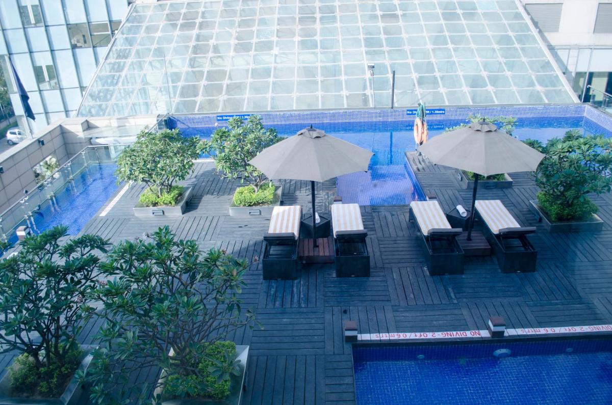 a pool with tables and umbrellas in a building at Radisson Blu Hotel, Greater Noida in Greater Noida