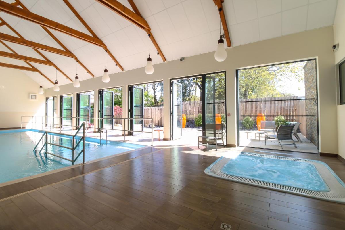 une piscine intérieure avec une grande pièce dotée de baies vitrées dans l'établissement Loire & Sens, à Juigné-sur-Loire