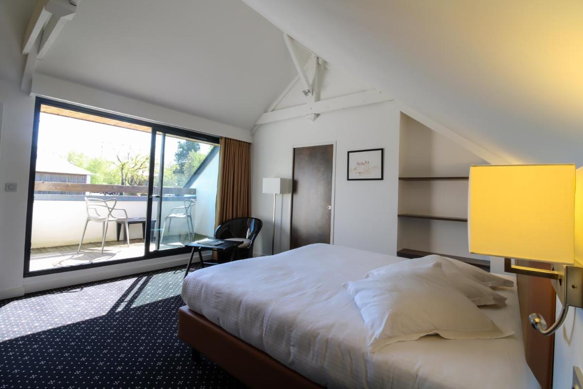 une chambre avec un lit et une grande fenêtre dans l'établissement Loire & Sens, à Juigné-sur-Loire