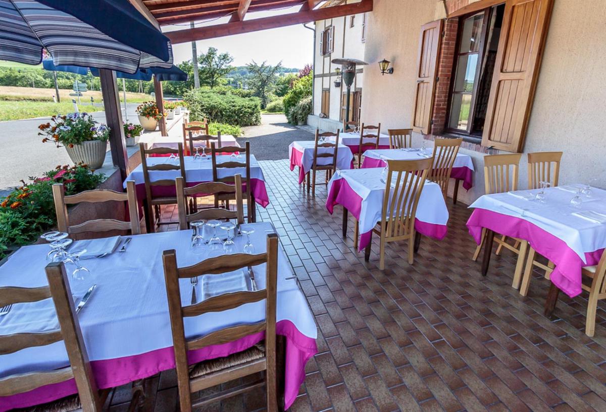 un restaurant avec des tables et des chaises recouvertes de nappes roses dans l'établissement Maison Legate "Hôtel Le Baudiere & Spa", à Saint-Beauzire