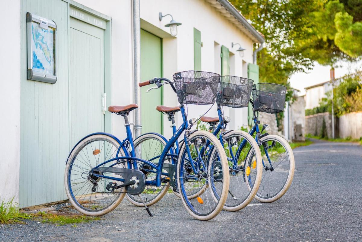 Trois vélos sont garés à côté d'un bâtiment dans l'établissement Hôtel Le Peu Breton, à Sainte-Marie de Ré