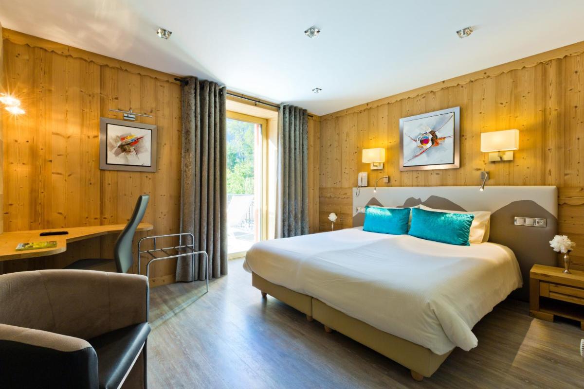 une chambre d'hôtel avec un grand lit et un bureau dans l'établissement Aiguille du Midi - Hôtel & Restaurant, à Chamonix-Mont-Blanc