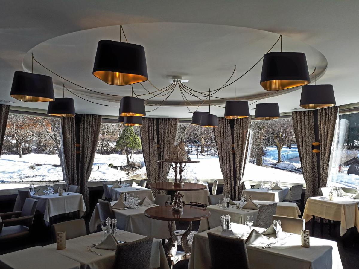 un restaurant avec des tables et des chaises blanches et des lustres dans l'établissement Aiguille du Midi - Hôtel & Restaurant, à Chamonix-Mont-Blanc