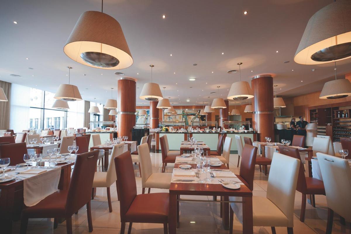 um restaurante com mesas e cadeiras e um bar em Vila Gale Santa Cruz em Santa Cruz - Madeira