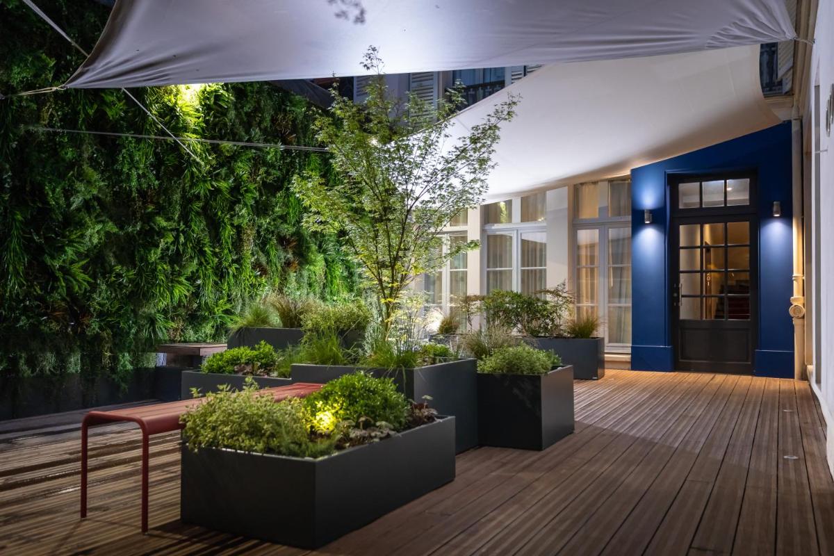 une cour avec des plantes en pot devant un bâtiment dans l'établissement Résidence & Spa Le Prince Régent, à Paris