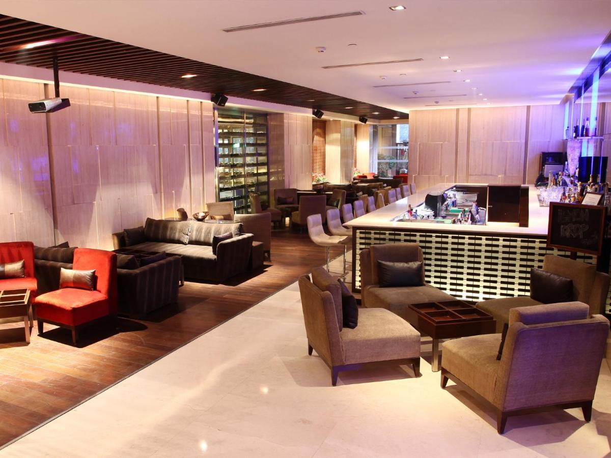 a lobby with couches and chairs and a bar at The LaLiT New Delhi in New Delhi