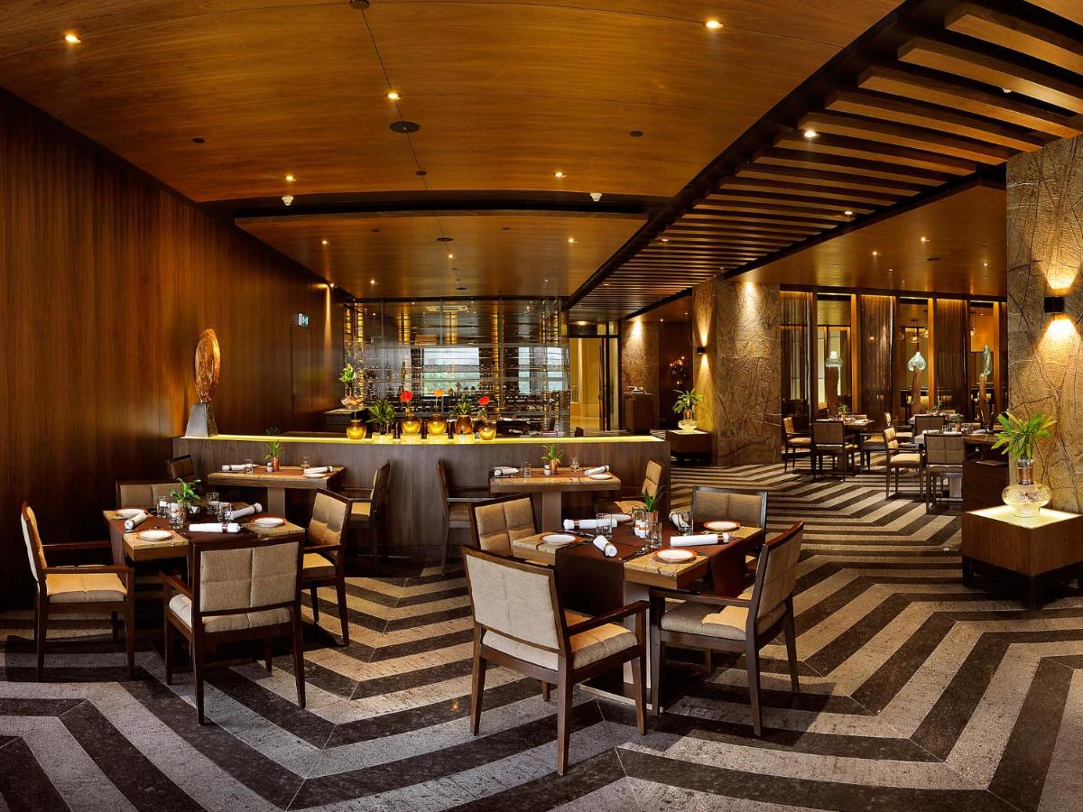 a restaurant with tables and chairs and a bar at The LaLiT New Delhi in New Delhi