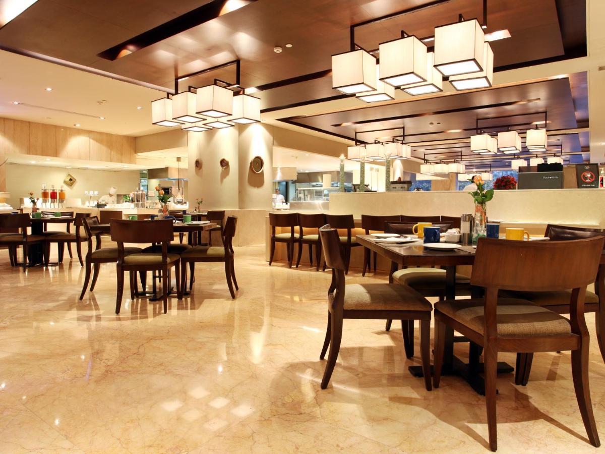 a dining room with tables and chairs in a restaurant at The LaLiT New Delhi in New Delhi