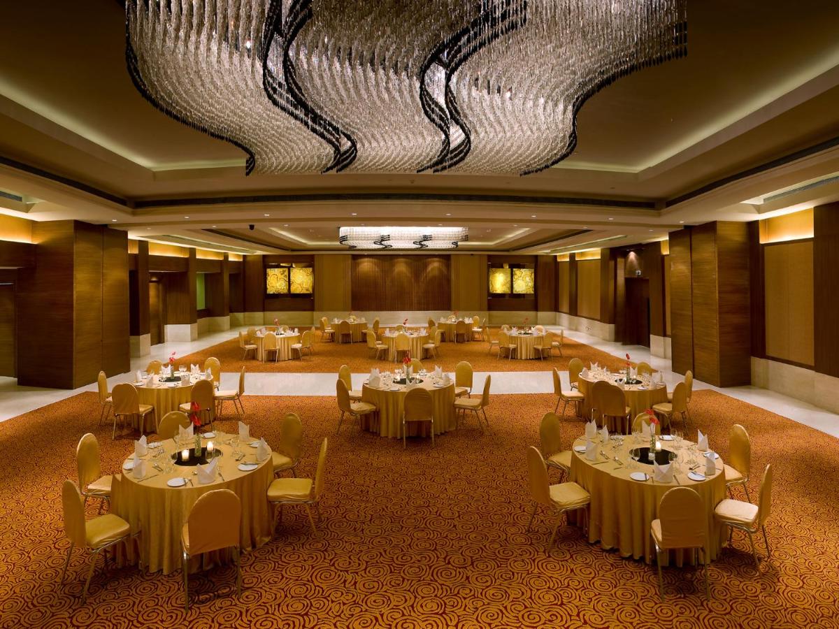 a banquet hall with tables and chairs in a room at The LaLiT New Delhi in New Delhi