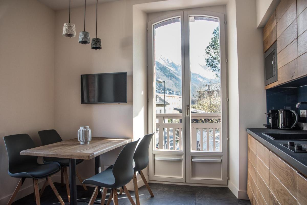 une cuisine avec une table et des chaises et une fenêtre dans l'établissement Appart'Hotel Aiguille Verte & Spa, à Chamonix-Mont-Blanc