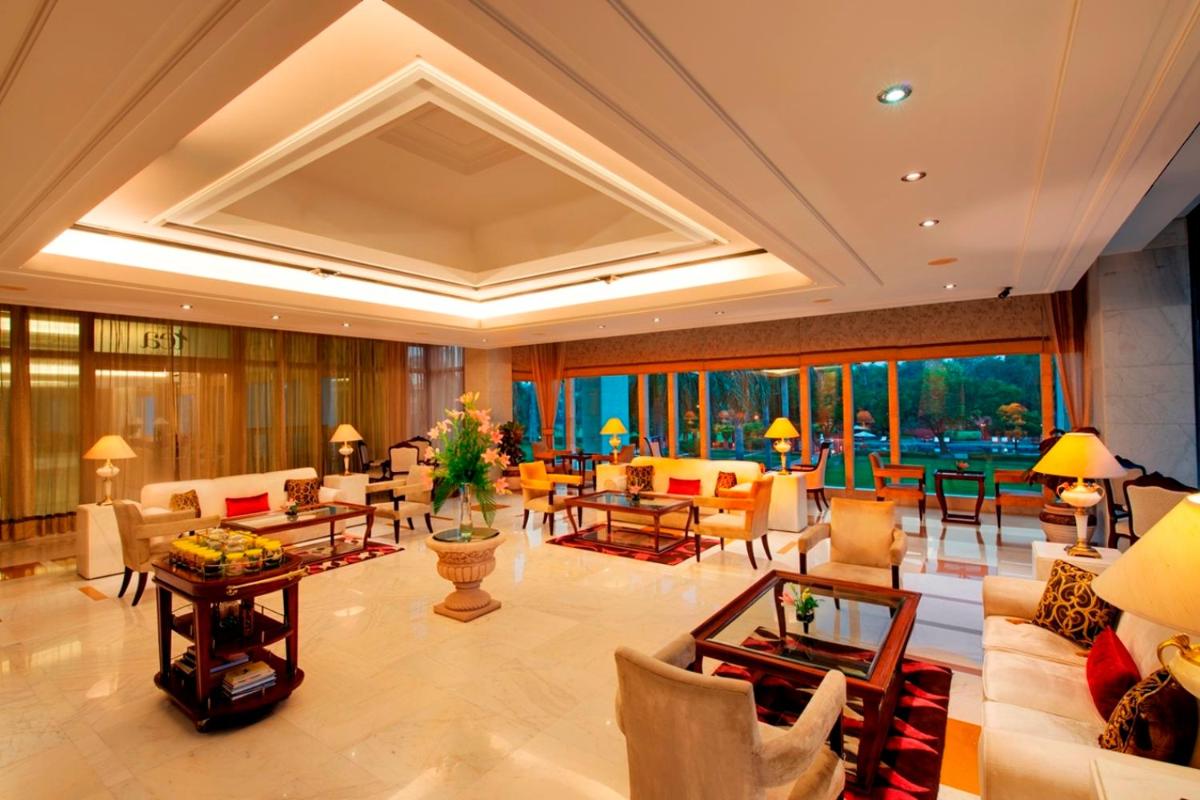 a large lobby with couches and tables and windows at Jaypee Palace Hotel in Agra