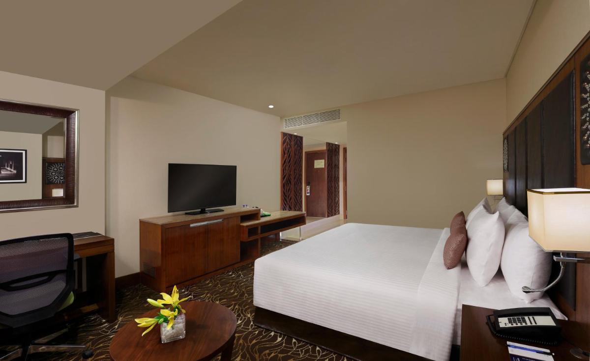 a hotel room with a bed and a television at Novotel Kochi Infopark in Cochin
