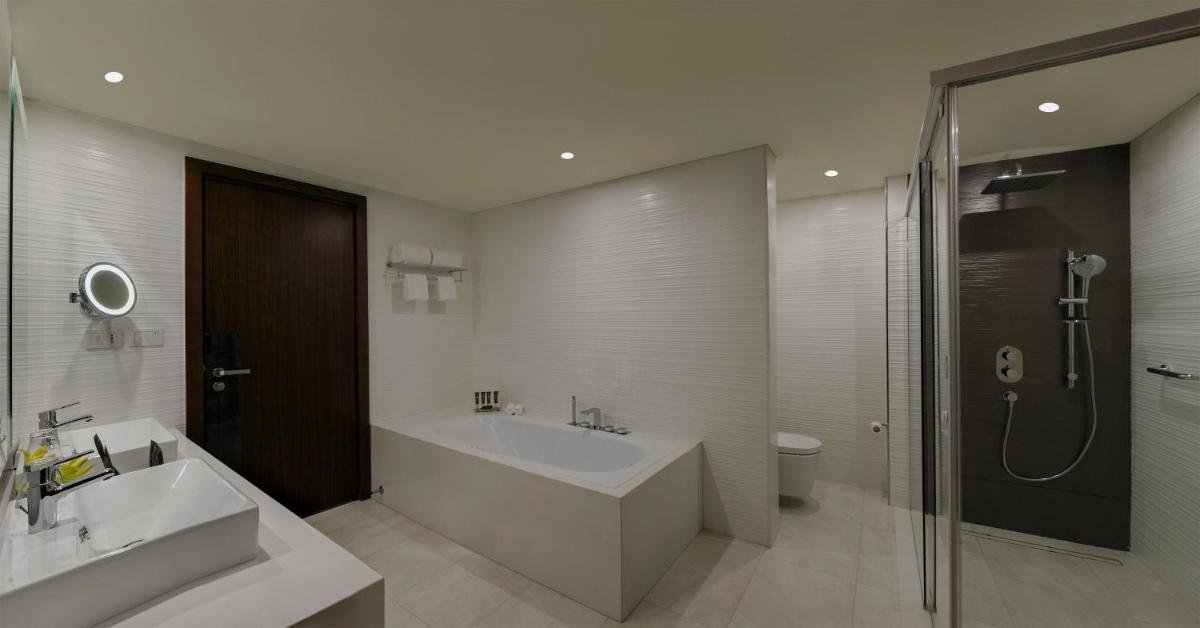 a bathroom with a tub and a sink and a shower at Novotel Kochi Infopark in Cochin