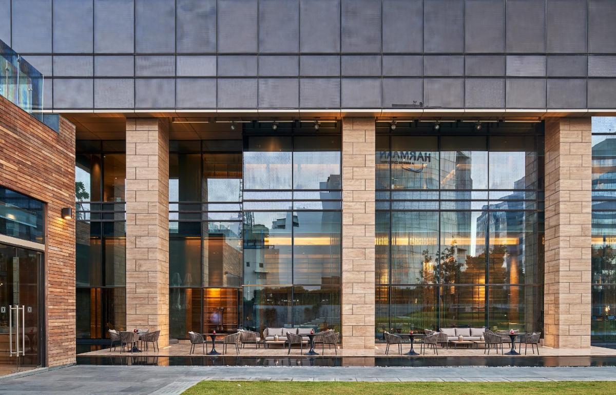 a large glass building with tables and chairs in it at The Den, Bengaluru in Bengaluru