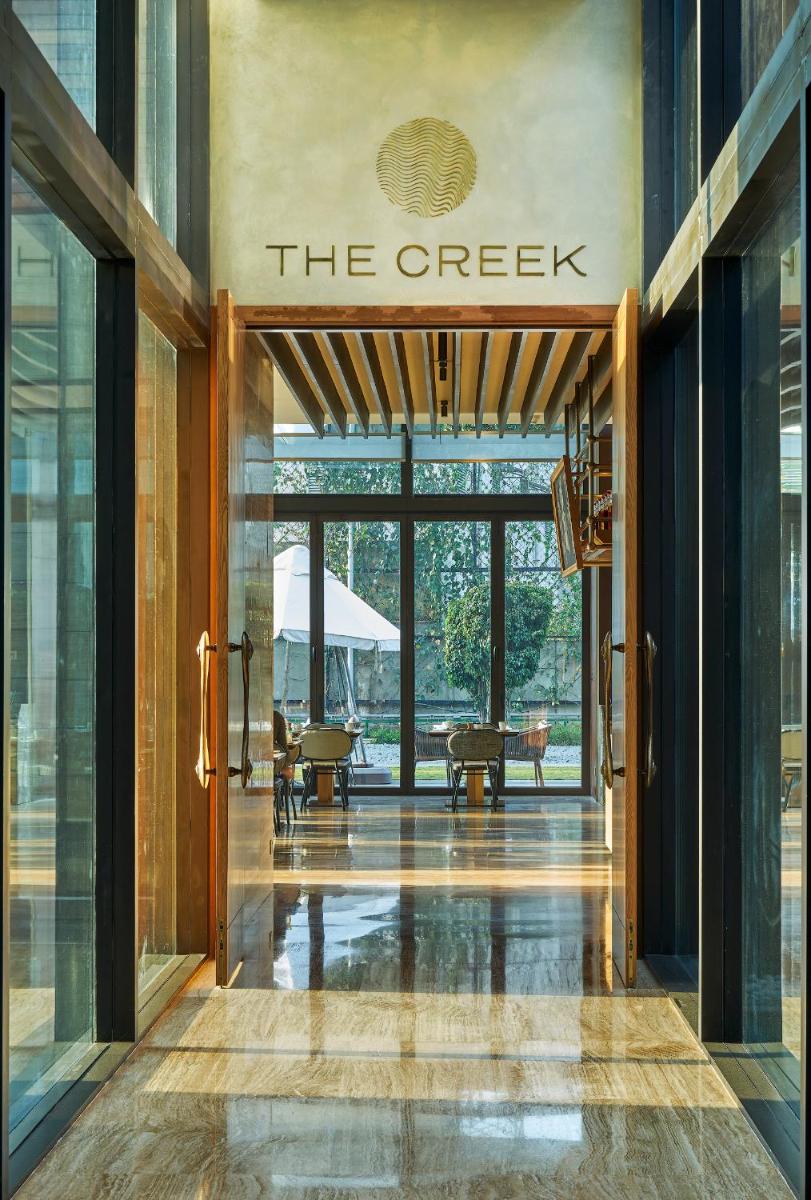 a lobby of a building with a sign that reads the creek at The Den, Bengaluru in Bengaluru