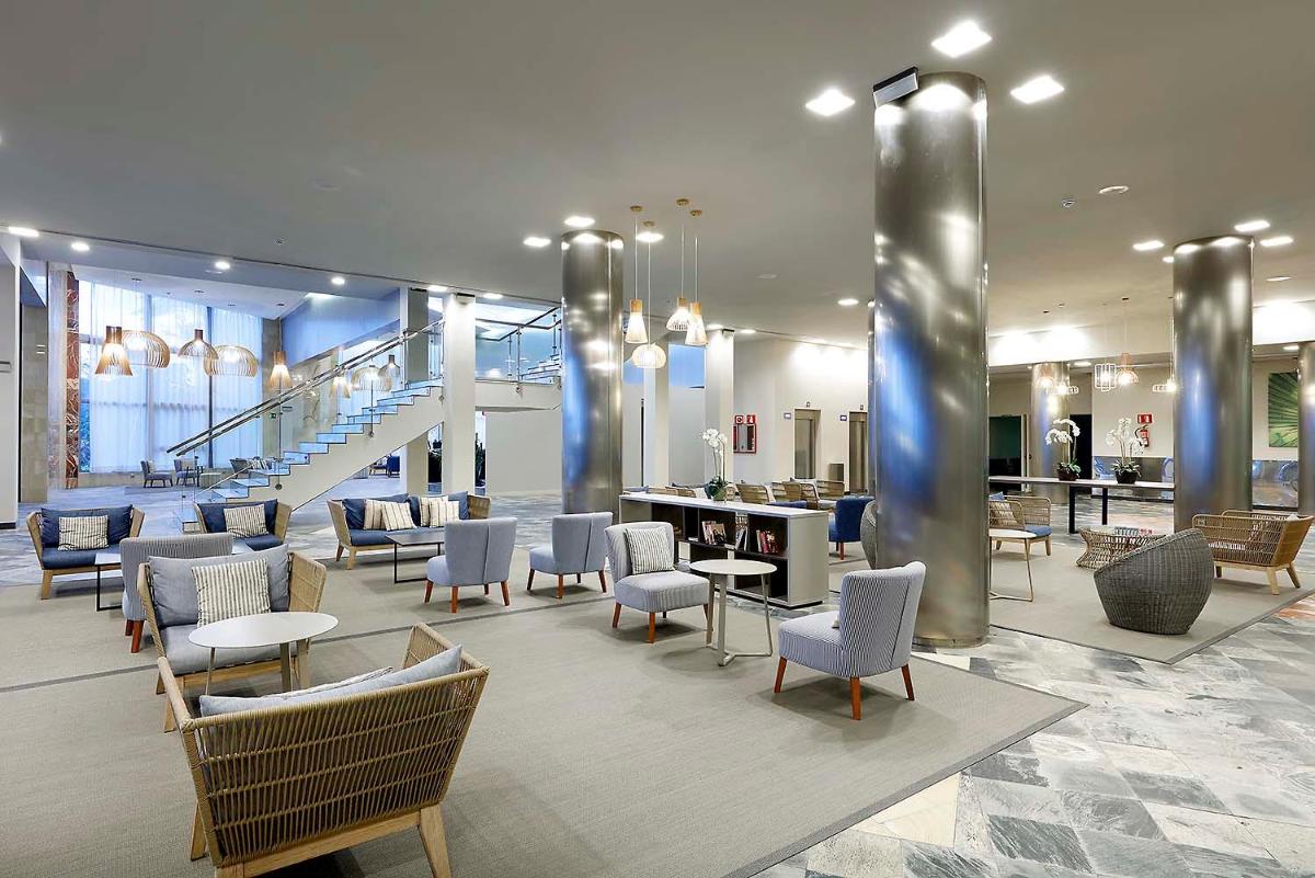 un vestíbulo con sillas y mesas y una escalera en Eurostars Las Salinas, en Caleta de Fuste