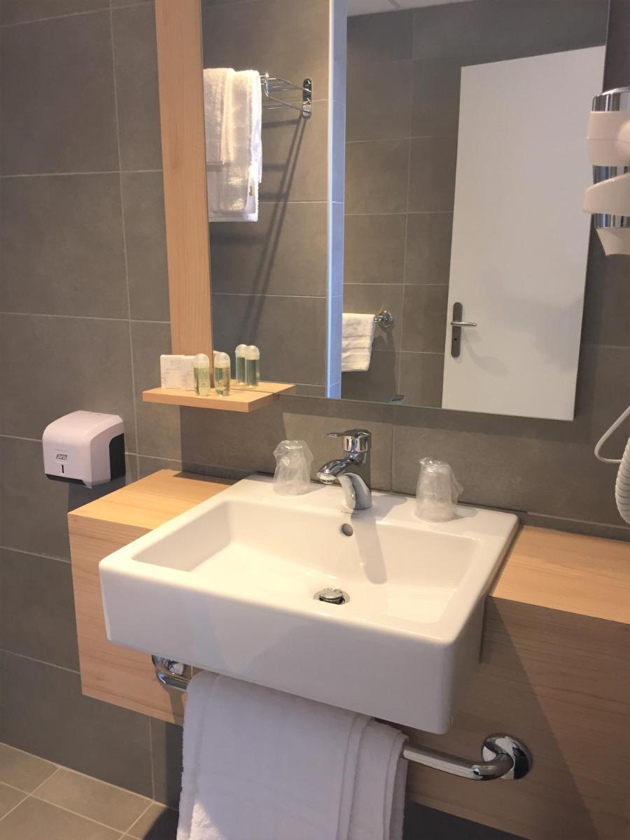 une salle de bain avec un lavabo blanc et un miroir dans l'établissement Le Felicien, à Saint-Félicien