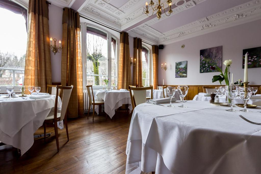 un restaurant avec deux tables avec des nappes blanches dans l'établissement Logis Hôtel Regina, à La Bourboule