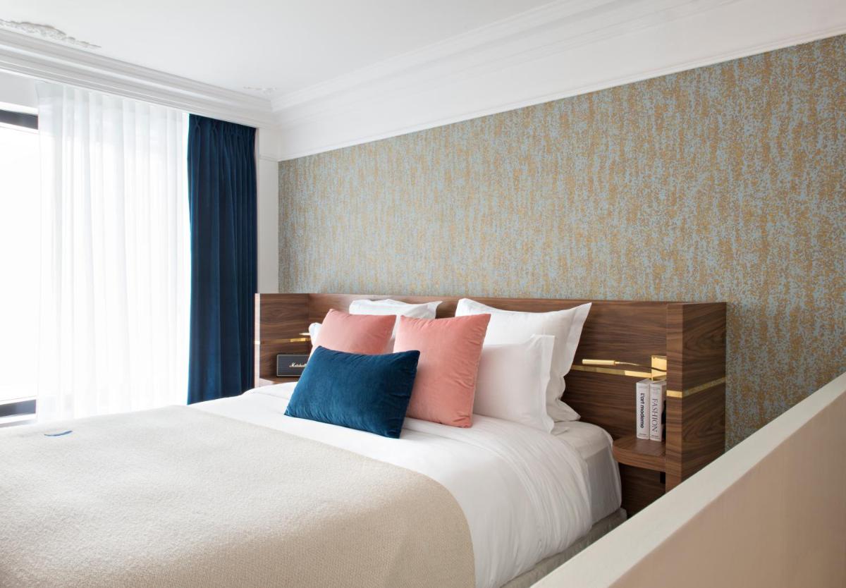 une chambre avec un grand lit avec des oreillers colorés dans l'établissement Hotel Parister Piscine & Spa, à Paris