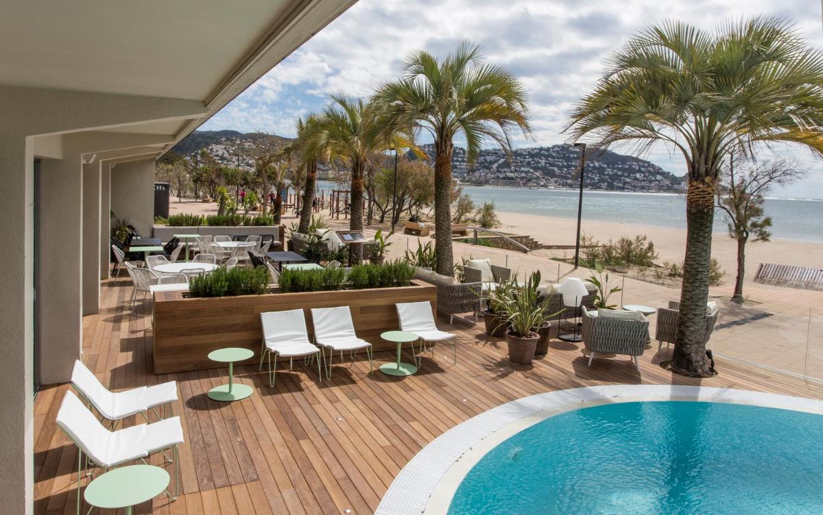 una piscina en una terraza con palmeras y una playa en Hotel Maritim 4 Superior, en Roses