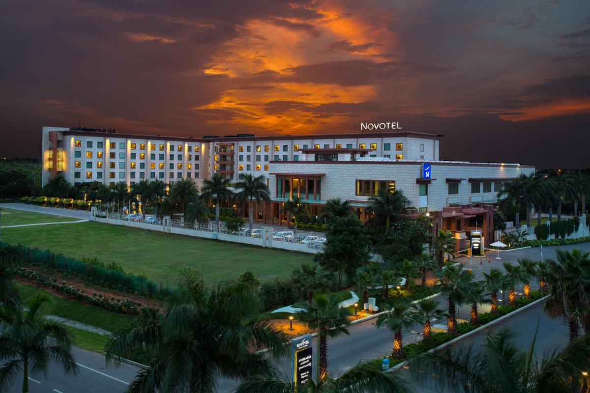 a view of a hotel at night with palm trees at Novotel Hyderabad Airport in Hyderabad