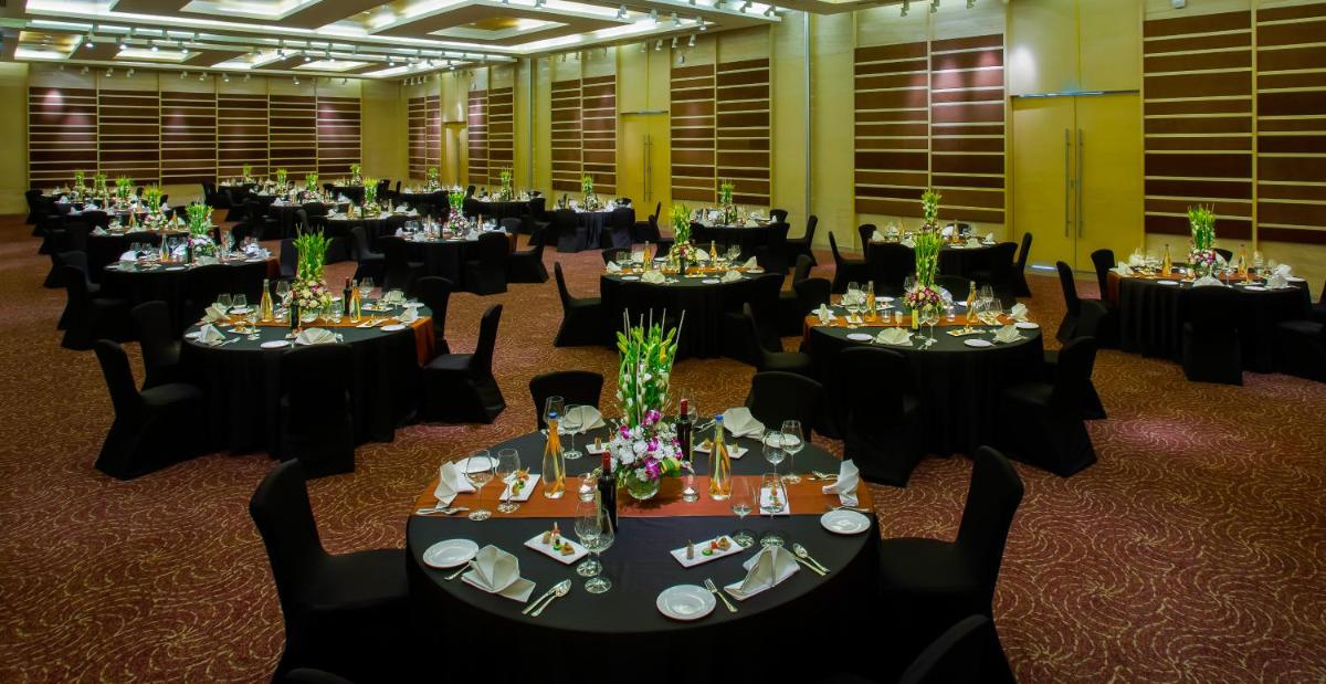 a large room with tables and chairs in a room at Novotel Hyderabad Airport in Hyderabad