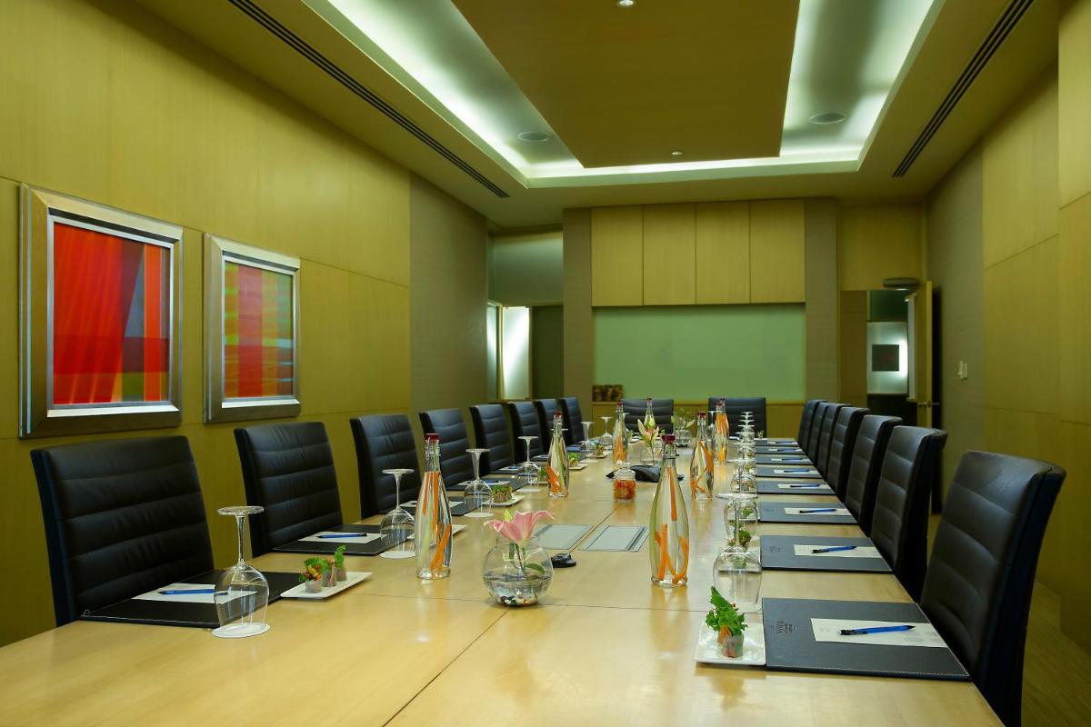 a conference room with a long table and chairs at Novotel Hyderabad Airport in Hyderabad