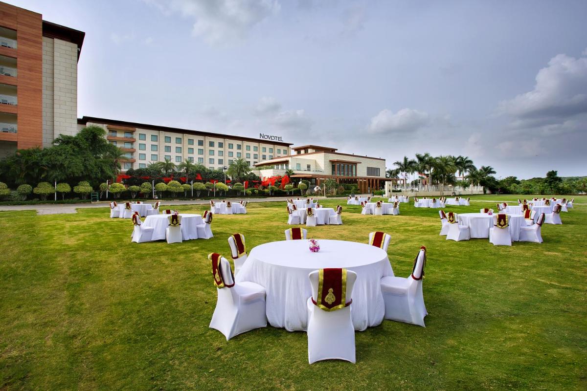 a group of white tables and chairs in a field at Novotel Hyderabad Airport in Hyderabad