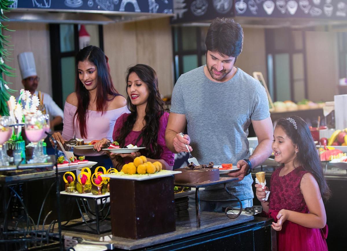 a group of people standing around a table with food at Novotel Hyderabad Airport in Hyderabad