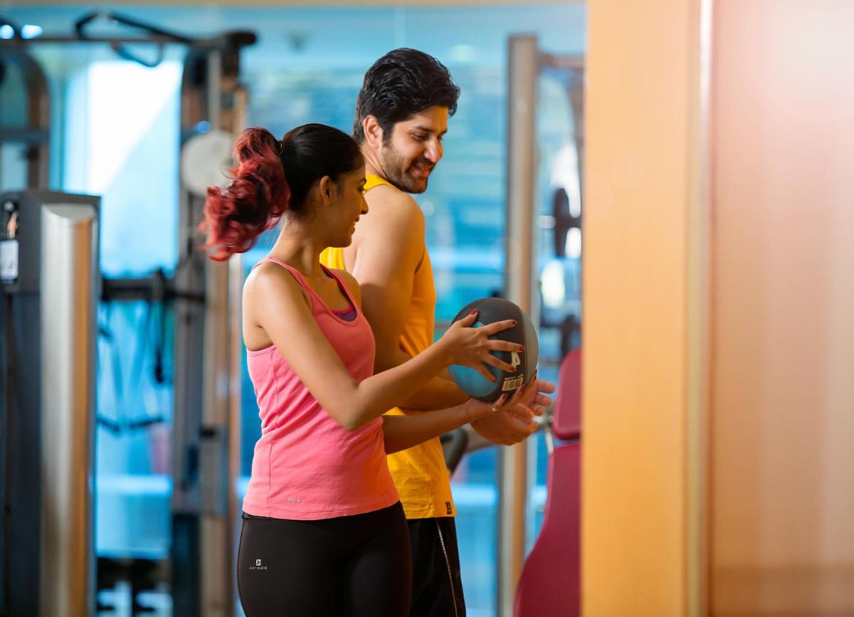 a man and a woman looking at a mirror in a gym at Novotel Hyderabad Airport in Hyderabad