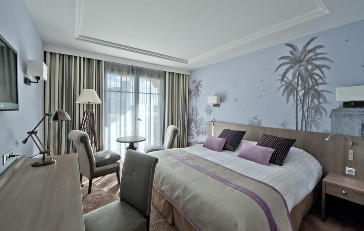 une chambre d'hôtel avec un grand lit avec des oreillers violets dans l'établissement Hôtel Le Nouveau Monde, à Saint-Malo 44 autres photos