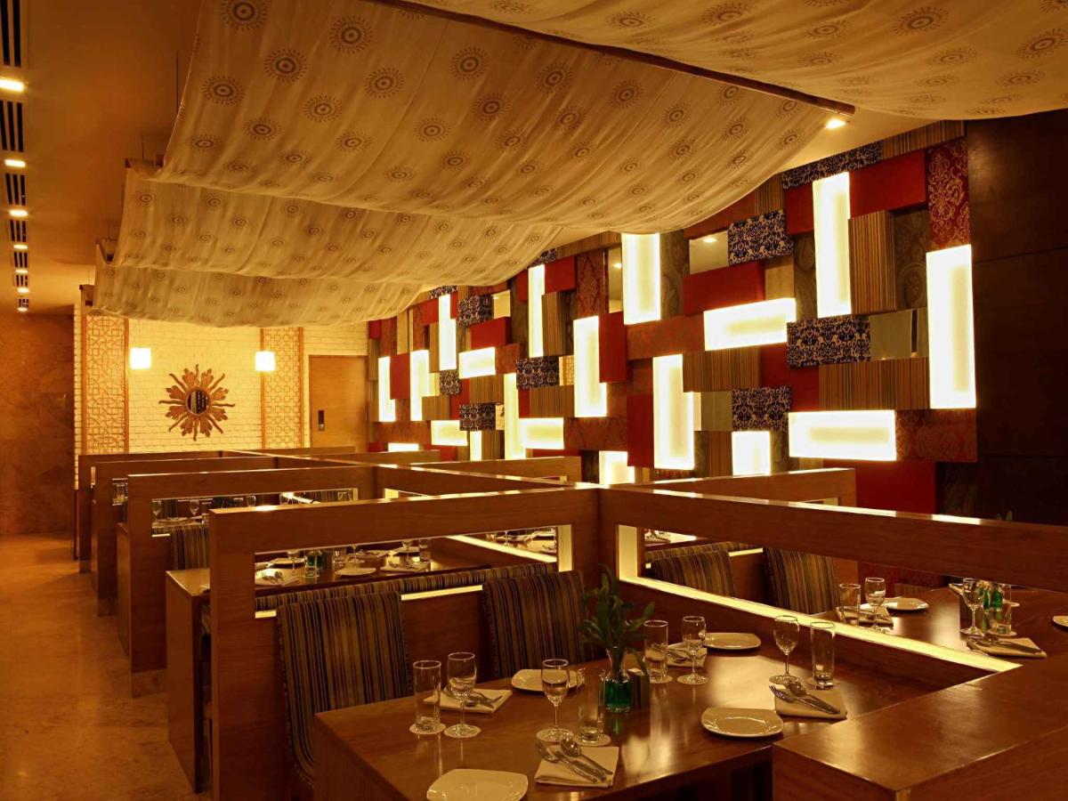 a restaurant with tables and chairs in a room at The Metropolitan Hotel & Spa New Delhi in New Delhi