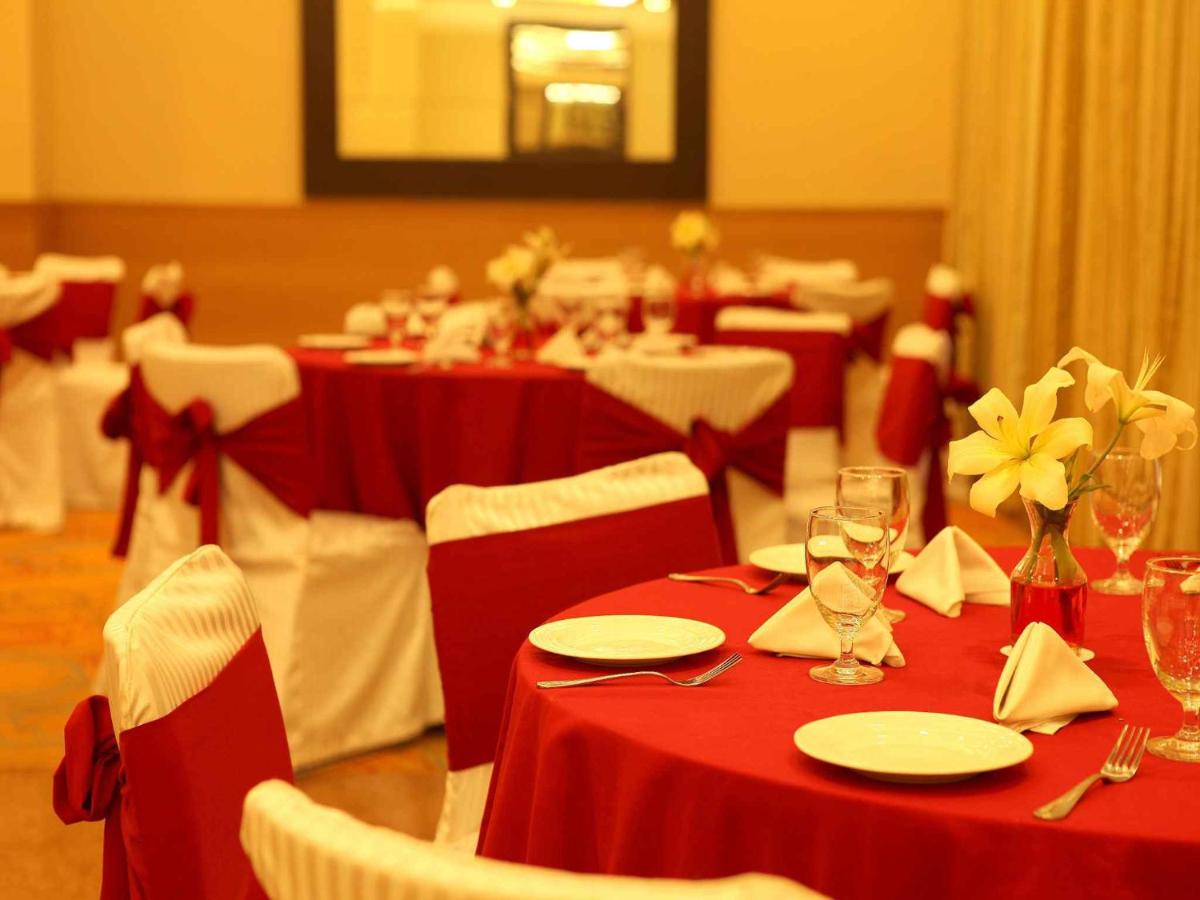 a dining room with red tables and chairs with glasses at The Metropolitan Hotel & Spa New Delhi in New Delhi +56 photos