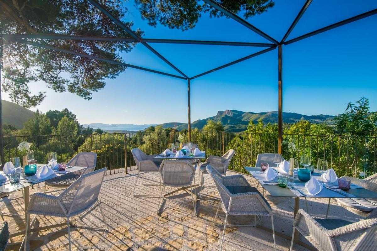 un patio con mesas y sillas y vistas a las montañas en Carrossa Hotel & Spa, en Artà