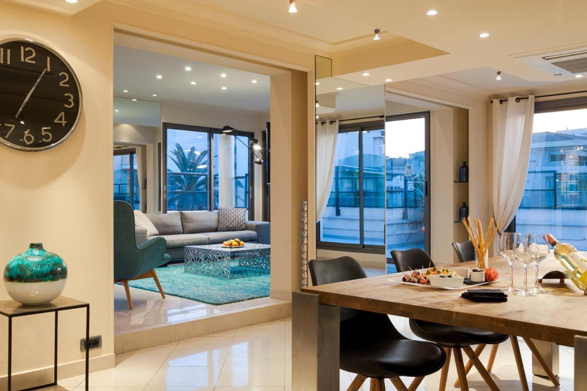 une salle à manger et un salon avec une grande horloge murale dans l'établissement Nehô Suites Cannes Croisette, à Cannes