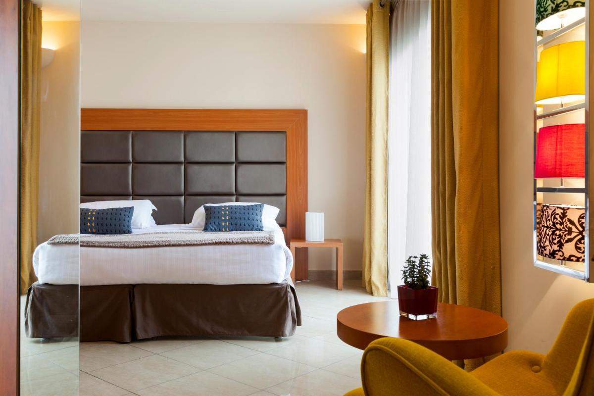une chambre d'hôtel avec un lit, une table et des chaises dans l'établissement Nehô Suites Cannes Croisette, à Cannes