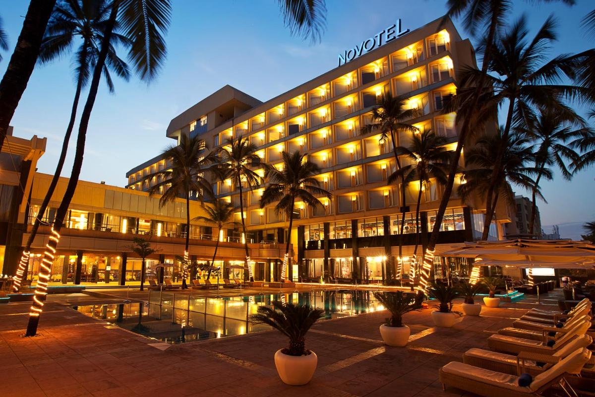 a hotel with a pool in front of a building at Novotel Mumbai Juhu Beach in Mumbai