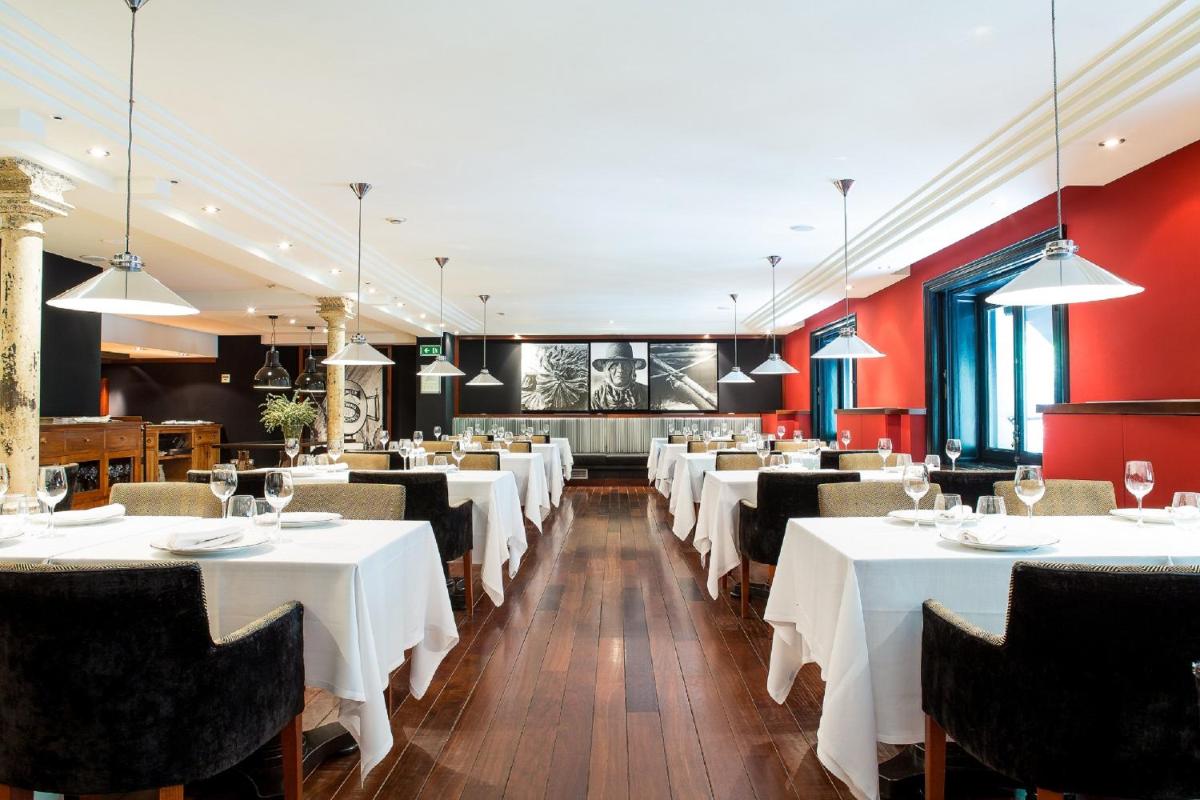 Un comedor con mesas y sillas blancas. en Hotel 1898, en Barcelona