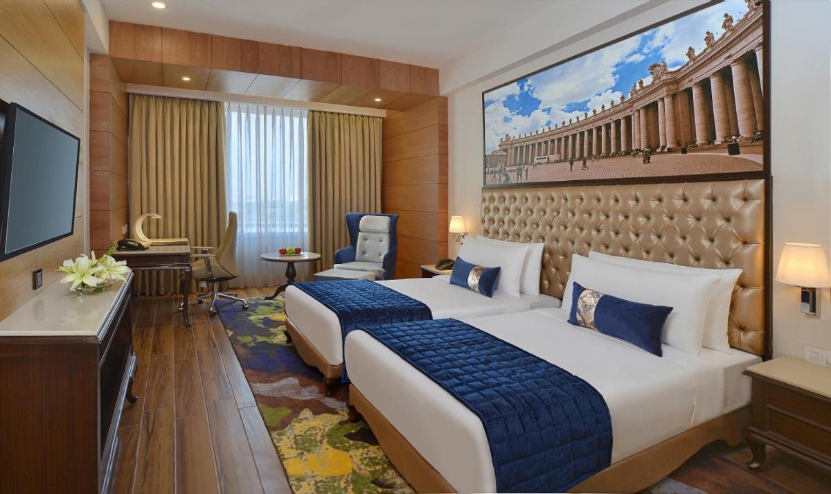 a hotel room with two beds and a flat screen tv at Radisson Chandigarh Zirakpur in Chandīgarh