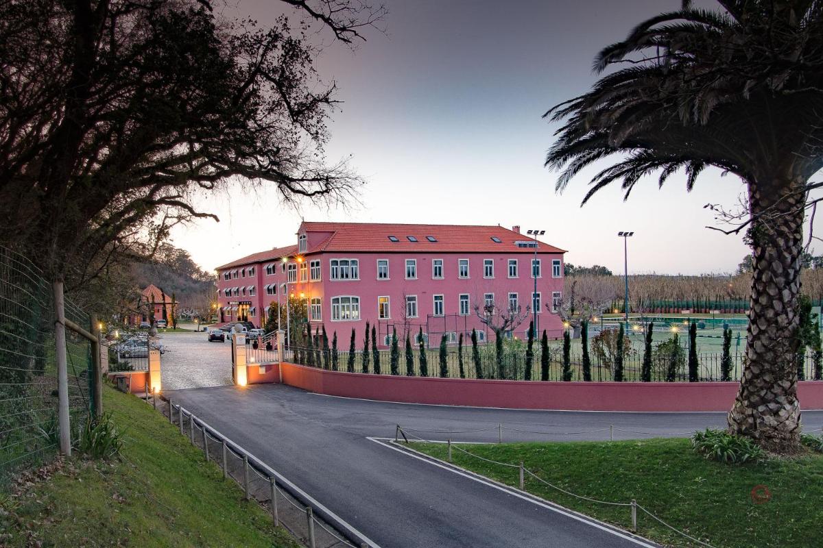 um grande edifício vermelho com uma palmeira na frente em Your Hotel & Spa Alcobaça em Alcobaça