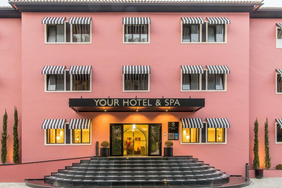 um prédio rosa com escadas que levam a um hotel em Your Hotel & Spa Alcobaça em Alcobaça