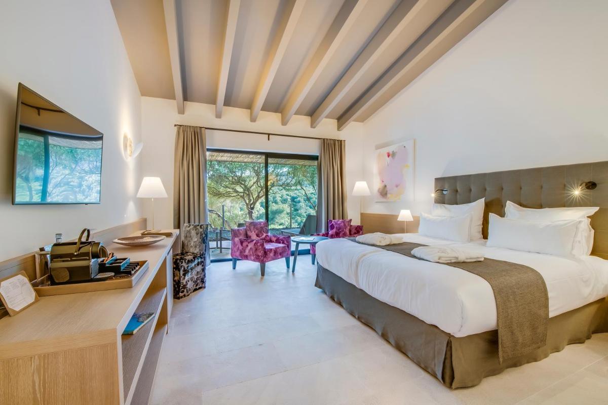 Una habitación de hotel con una cama grande y un escritorio. en Carrossa Hotel & Spa, en Artà