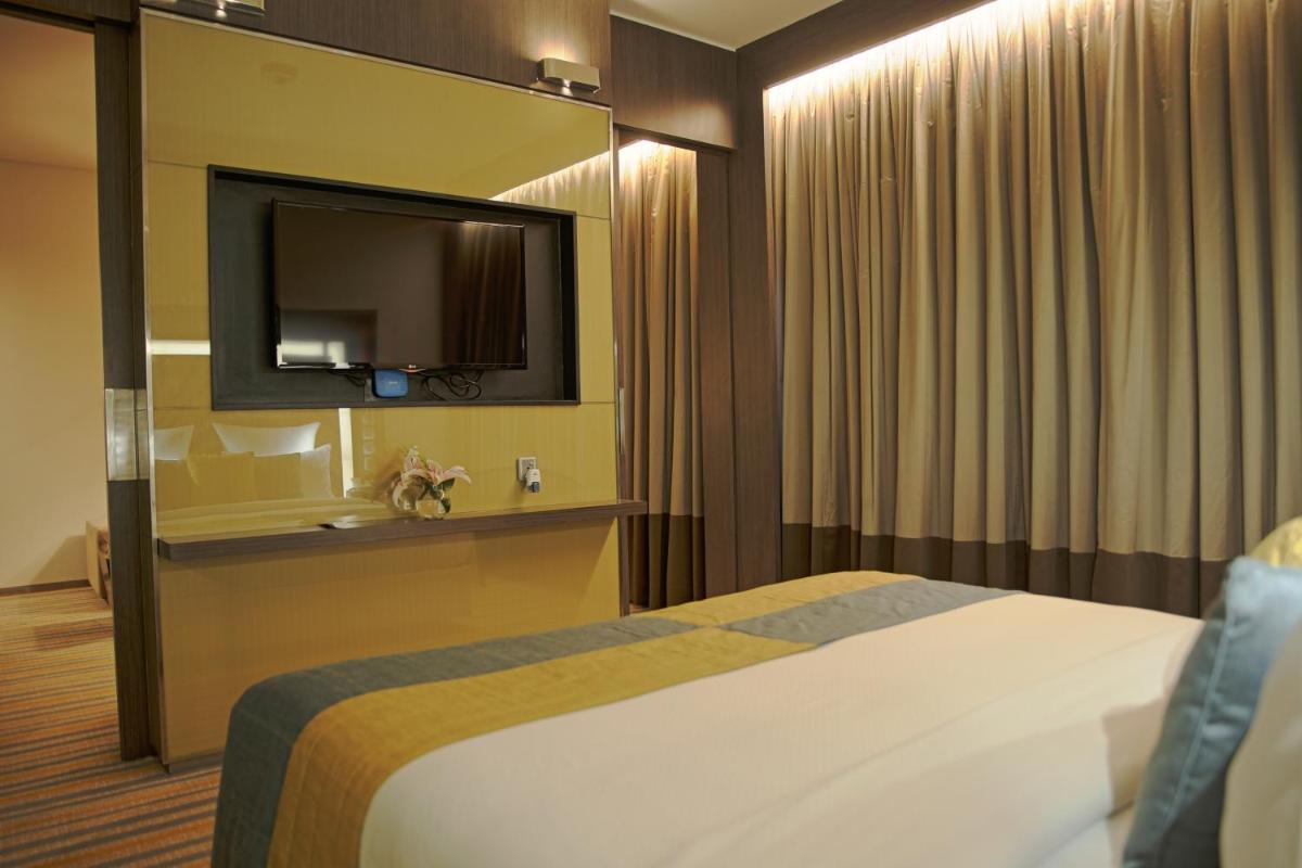 a hotel room with a bed and a flat screen tv at Novotel Kolkata Hotel and Residences in Kolkata a hotel room with a bed and a flat screen tv at Novotel Kolkata Hotel and Residences in Kolkata