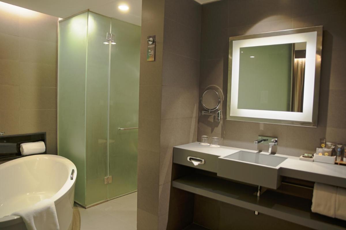 a bathroom with a sink and a shower and a mirror at Novotel Kolkata Hotel and Residences in Kolkata a bathroom with a sink and a shower and a mirror at Novotel Kolkata Hotel and Residences in Kolkata