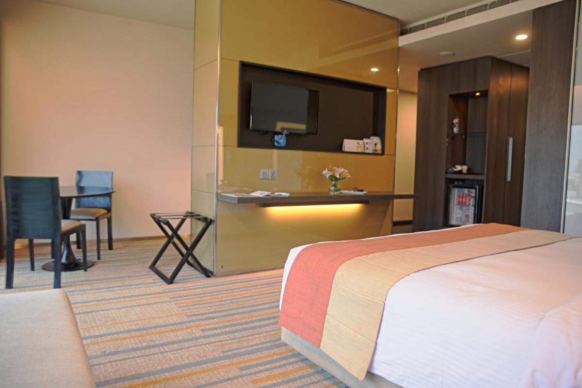 a hotel room with a bed and a flat screen tv at Novotel Kolkata Hotel and Residences in Kolkata a hotel room with a bed and a flat screen tv at Novotel Kolkata Hotel and Residences in Kolkata