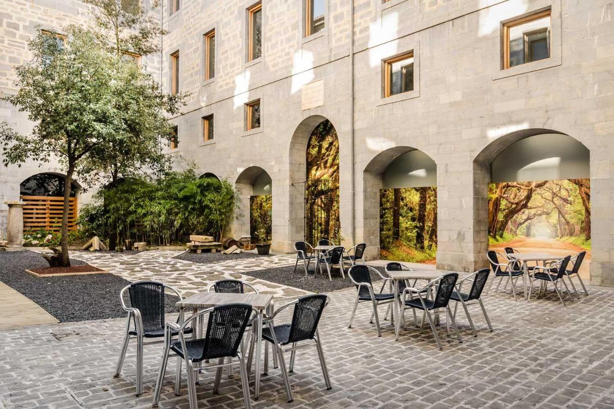 Un patio con mesas y sillas frente a un edificio. en Hotel Balneario Orduña Plaza, en Orduña