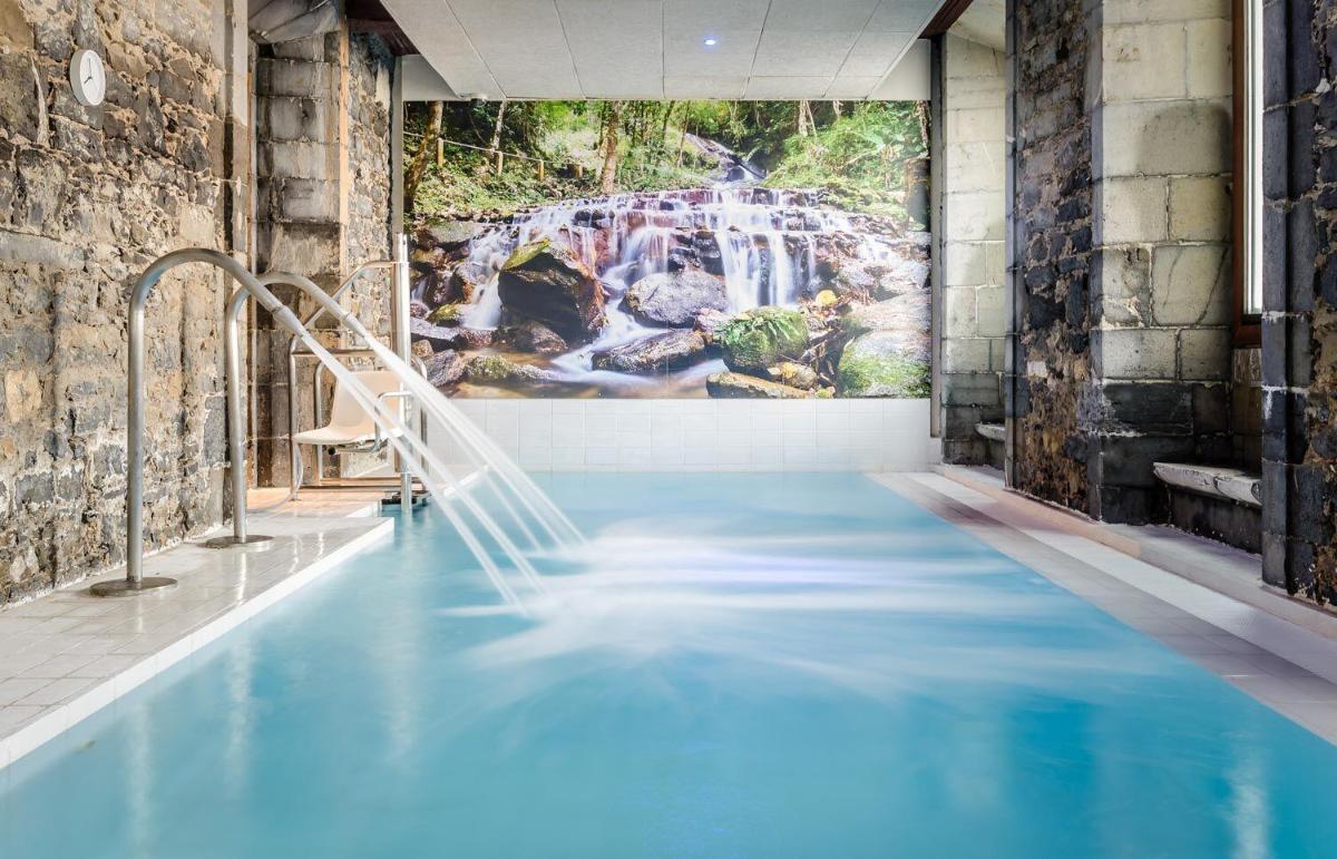 una piscina con un mural de cascada en la pared en Hotel Balneario Orduña Plaza, en Orduña