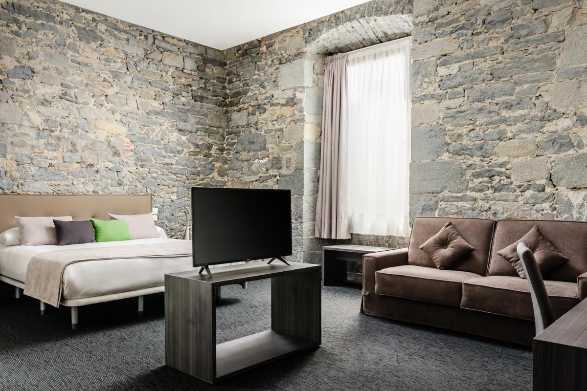 Un dormitorio con una cama, un televisor y un sofá. en Hotel Balneario Orduña Plaza, en Orduña