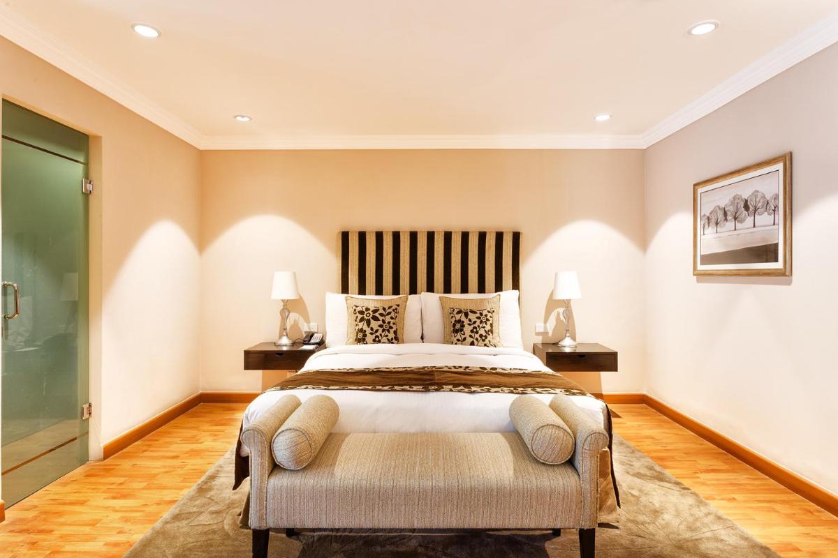 a bedroom with a large bed and two lamps at The Claridges New Delhi in New Delhi a bedroom with a large bed and two lamps at The Claridges New Delhi in New Delhi